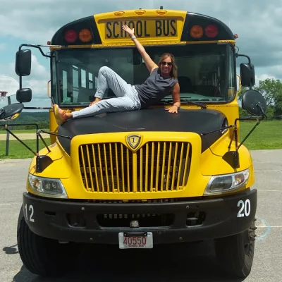 a woman lying on the hood of a school bus